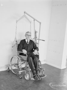 Welfare Department, taken for Social Services Dagenham Town Show display, showing male wheelchair user sitting upright in chair with equipment, 1972