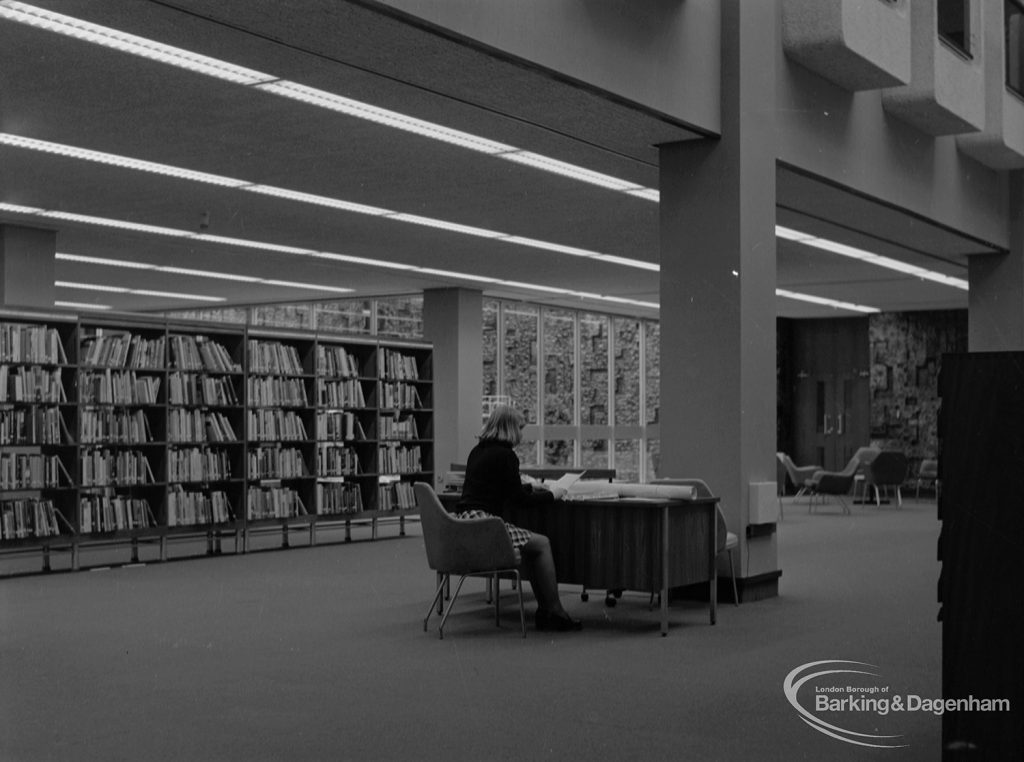 New Barking Central Library, Axe Street, Barking, showing architecture, bookcases, and Mrs Harrison at desk in Lending section, 1974
