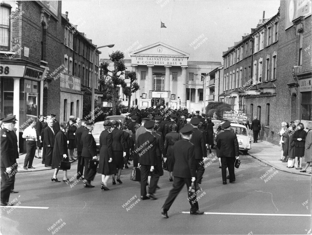 The Salvation Army Congress Hall (now Clapton Girls’ Academy, formerly London Orphan Asylum and in early c.19th the site of Newcome’s Academy for Boys). Includes arrival of centenary procession from the junction of Linscott and Lower Clapton Roads. Large crown of men and women in Salvation Army uniforms, 1965.