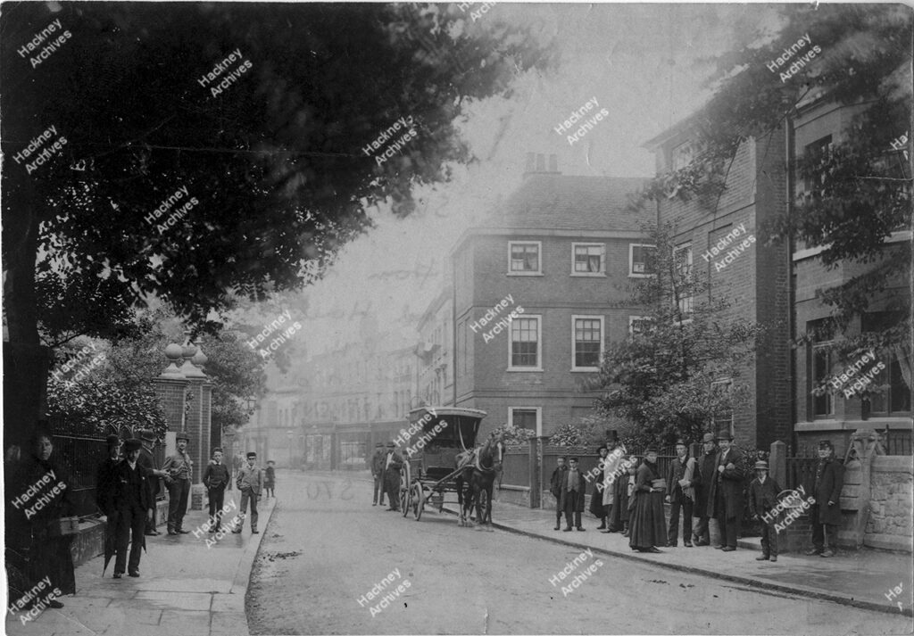 Stoke Newington Church Street looking east from old St Mary’s. Includes Halstead House on right. Rose and Crown public house on the east side of Albion Road and a horse drawn baker’s cart. Men women and children in Victorian dress, c.1880