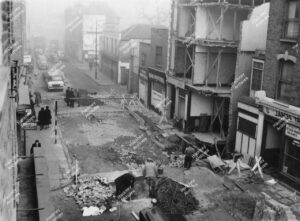 Subsidence beneath a pet shop and former Falcon public house building on Stoke Newington Church Street. Front of building collapsed. Includes workmen cornering the area off in road. 1959.
