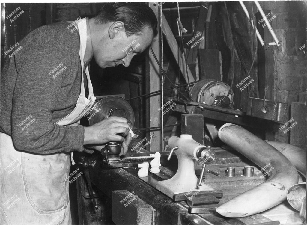 Craftsman turning ivory chess men, Hackney, c.1960.