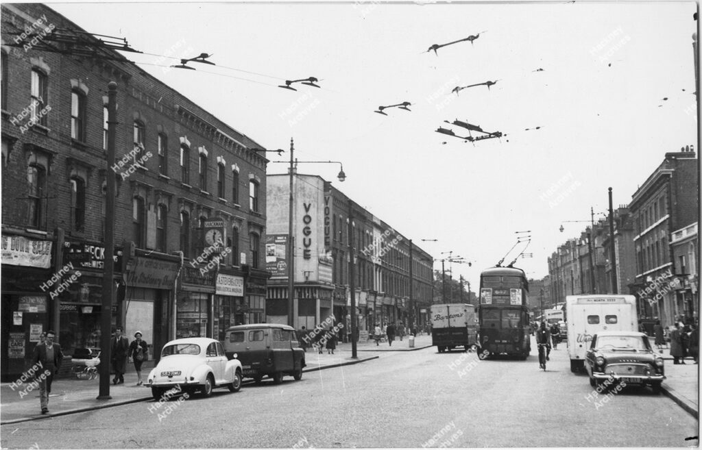 Stoke Newington High Street, numbers 62-2 west side with junction to Hollar Road on left. Includes the Vogue cinema and trolley bus. May 1961.