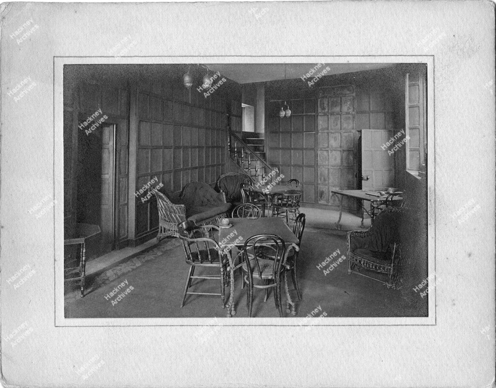 Interior of Sutton House, Homerton High Street, Homerton, Hackney, c.1905. The Cromwell panelled room and fireplace at Sutton House (St John’s Church Institute). Includes electric bulbs and lamps.