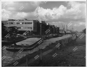The Lesney Matchbox Factory, Lee Conservancy Road, Hackney. View from the east side of River Lea Navigation. Includes barges on the river and loading cranes in the background, 1966.