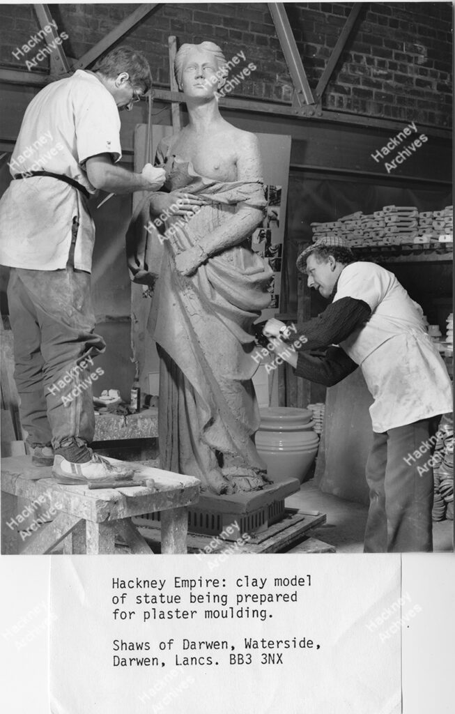 Two men moulding the clay model statue in preparation for it to be placed on the roof of the Hackney Empire, Mare Street, c.1987.