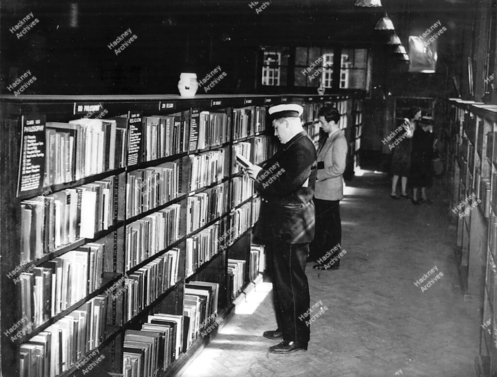 Milkman browsing at shelves in library, c.1950.