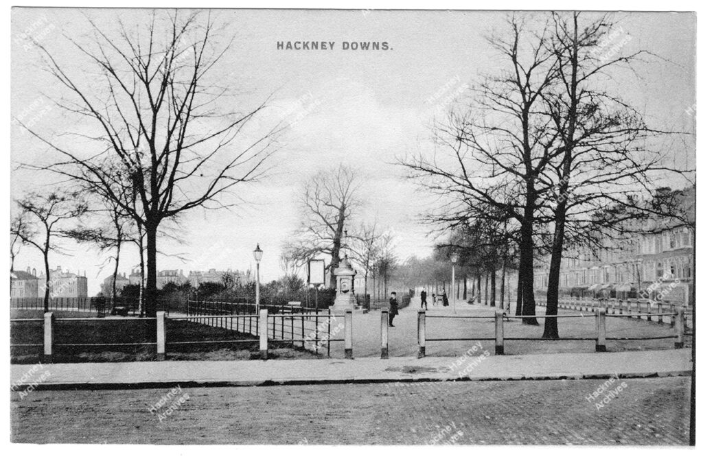 Hackney Downs from the junction of Queensdown and Downs Park Roads. Showing drinking fountain and part of Downs Road and Queensdown Road, c.1920.