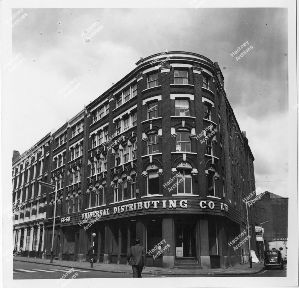 Graham Road with junction with Massie Road and Fassett Square, Dalston, Hackney. Includes adverts for the Conservative Party and Double Diamond beer on side of house. 1964.