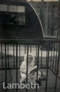 BABY OUTSIDE A WARTIME PREFAB: BRIXTON NORTH