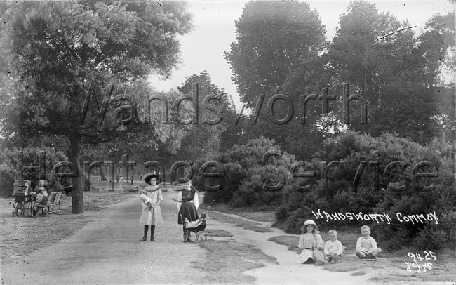 Wandsworth Common – children sitting on grass, woman with pram